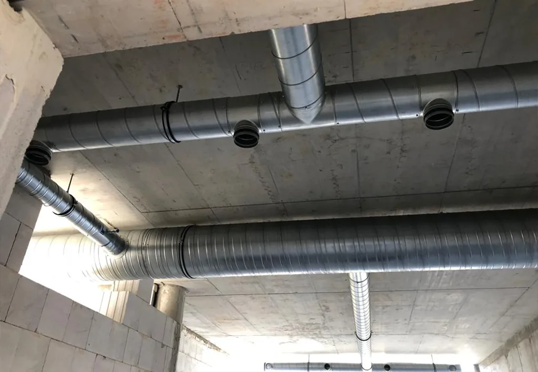 Verlegte Wickelfalzrohre einer Lüftungsanlage unter der Decke einer Tiefgarage